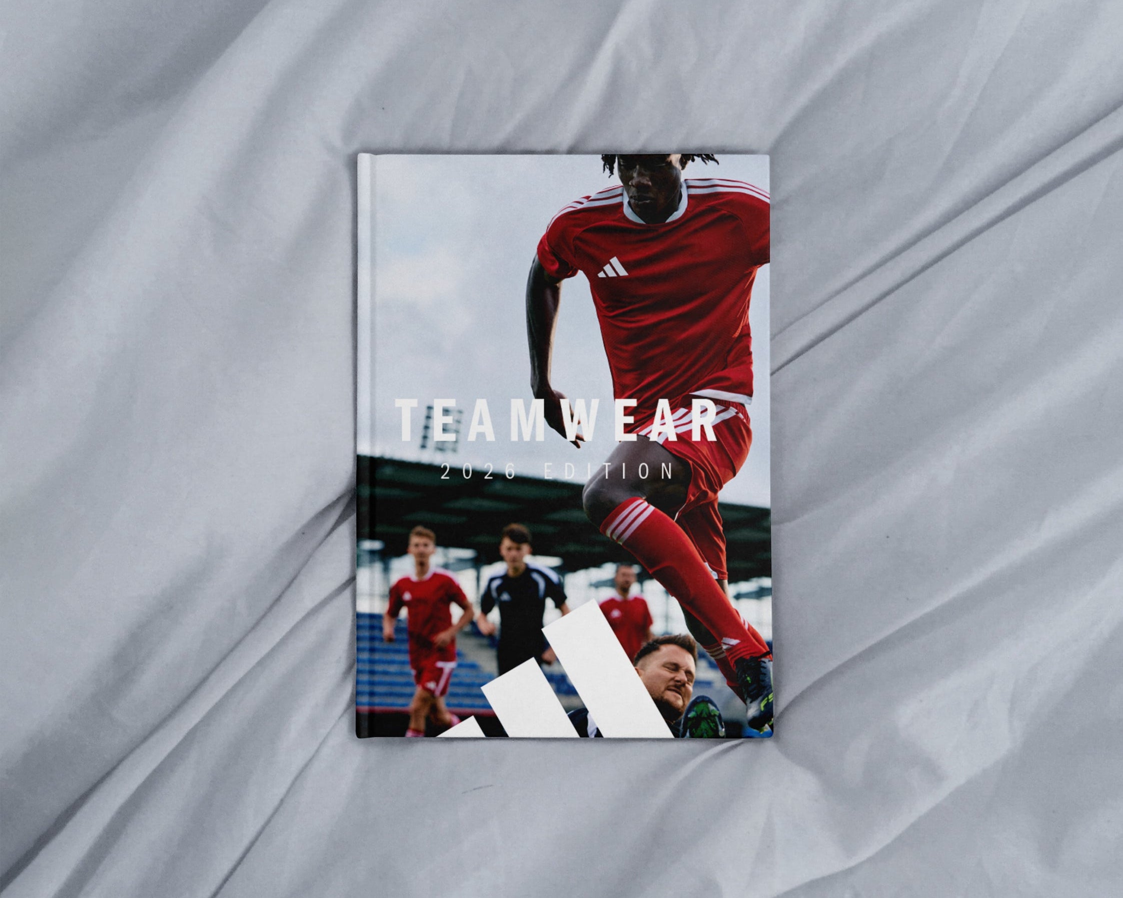 Brochure or catalog cover featuring a soccer player in red uniform on a gray fabric background